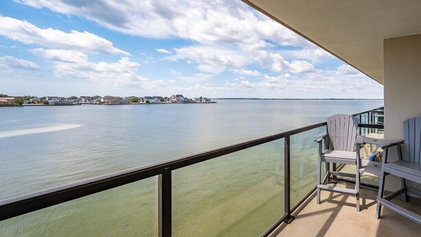 Un balcon donnant sur une étendue d’eau paisible et une côte lointaine.