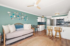 A bedroom with a bed, a desk, and a chair, a kitchenette with a fridge, stove, and microwave, and a ceiling fan. - Bayfront Condo with Great Views and Nice Amenities (Ocean City)