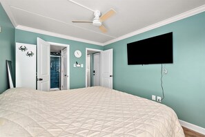 A bedroom with a bed, a ceiling fan, a TV, and a door leading to a bathroom. - Bayfront Condo with Great Views and Nice Amenities (Ocean City)