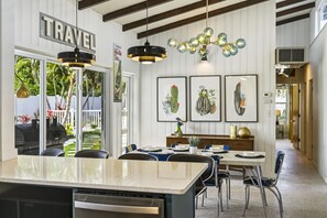 A kitchen with a central island, a dining area with chairs, a hanging light fixture, and framed cactus artwork on the wall. - Entire Home | Sleeps 14 | Putt Putt Golf |Canal Views (Bradenton)