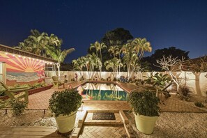 A swimming pool with a sunset mural, palm trees, and a brick pathway leading to the pool. - King Beds | Game Room | Putt Putt | Pool | (Bradenton)