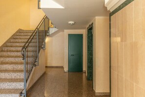 Ein Flur mit Treppe, einer grünen Tür und einer Marmorwand.