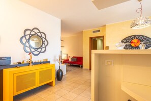 Un salon moderne avec une console jaune, un canapé rouge et un élément décoratif mural.