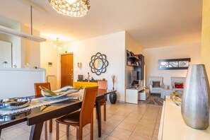 Ein modernes Wohnzimmer mit Essbereich, einer Sofagarnitur, einem Couchtisch und einem Wanddekor.