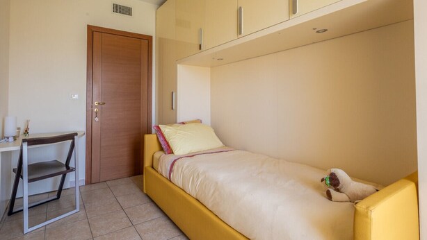 Ein kleines Zimmer mit einem Bett, einem Schreibtisch und einem Stuhl.