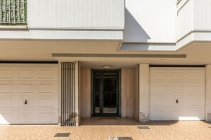 Un bâtiment doté de deux portes de garage, d’une entrée centrale avec une porte et d’un sol carrelé.