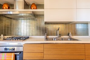 Une cuisine moderne équipée d’une cuisinière à gaz, d’un évier en acier inoxydable et de meubles en bois.