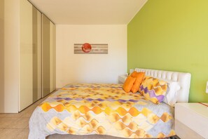 Une chambre à coucher avec un lit, une table de chevet, une œuvre d’art accrochée au mur et un mur d’accent de couleur verte.