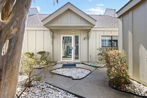A residential house with a front door, a small garden with pebbles, and a tree. - Fully Renovated Villa - Sleeps 6 Near Beach & Golf (Hilton Head Island)