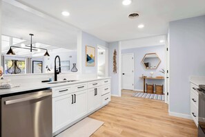 A modern kitchen with white cabinets, stainless steel appliances, and pendant lighting. - Fully Renovated Villa - Sleeps 6 Near Beach & Golf (Hilton Head Island)