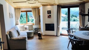 Una sala de estar acogedora con un sofá, una mesita, una chimenea y un comedor con sillas.