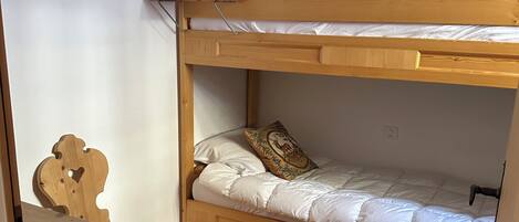A bunk bed with a wooden headboard, a chair, and a fur rug on the floor.