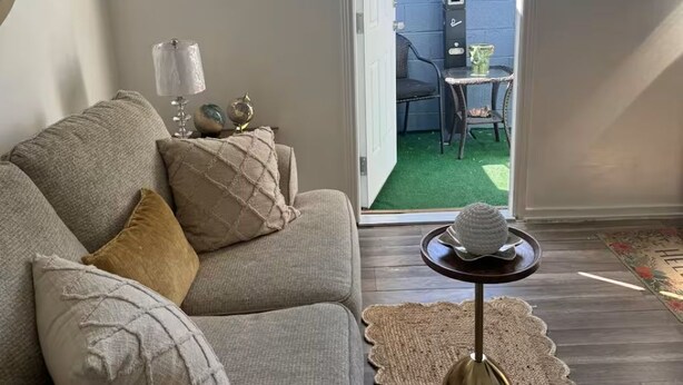 A living room with a sofa, a coffee table, and a door leading to an outdoor area with a table and chairs. - Tranquil stay Vegas (Las Vegas)