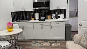 A compact kitchen with white cabinets, a microwave, and a coffee maker. - Tranquil stay Vegas (Las Vegas)