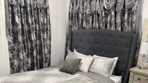 A bedroom with a large bed, a nightstand, a rug, and curtains. - Tranquil stay Vegas (Las Vegas)