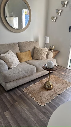 Un salon avec un canapé, un miroir rond, une lampe et des papillons décoratifs accrochés au mur.