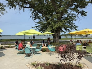 An outdoor seating area with tables and chairs under yellow umbrellas, overlooking a body of water. - One bedroom  in United States of America, Sandusky (Sandusky)