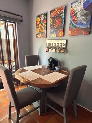 A dining area with a round table, chairs, a coffee machine, and wall art. - Zona Romantica Oasis/Pool/2 block Pier bars shop (Puerto Vallarta)