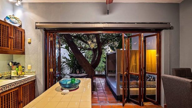 A kitchen with a large island, a dining area with a table and chairs, and a sliding glass door leading to an outdoor patio. - Zona Romantica Oasis/Pool/2 block Pier bars shop (Puerto Vallarta)
