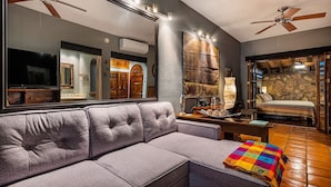 A living room with a grey sofa, a colorful throw blanket, a stone fireplace, and a large mirror. - Zona Romantica Oasis/Pool/2 block Pier bars shop (Puerto Vallarta)