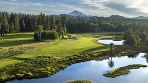 Camp de golf amb un estany, arbres i una muntanya al fons.