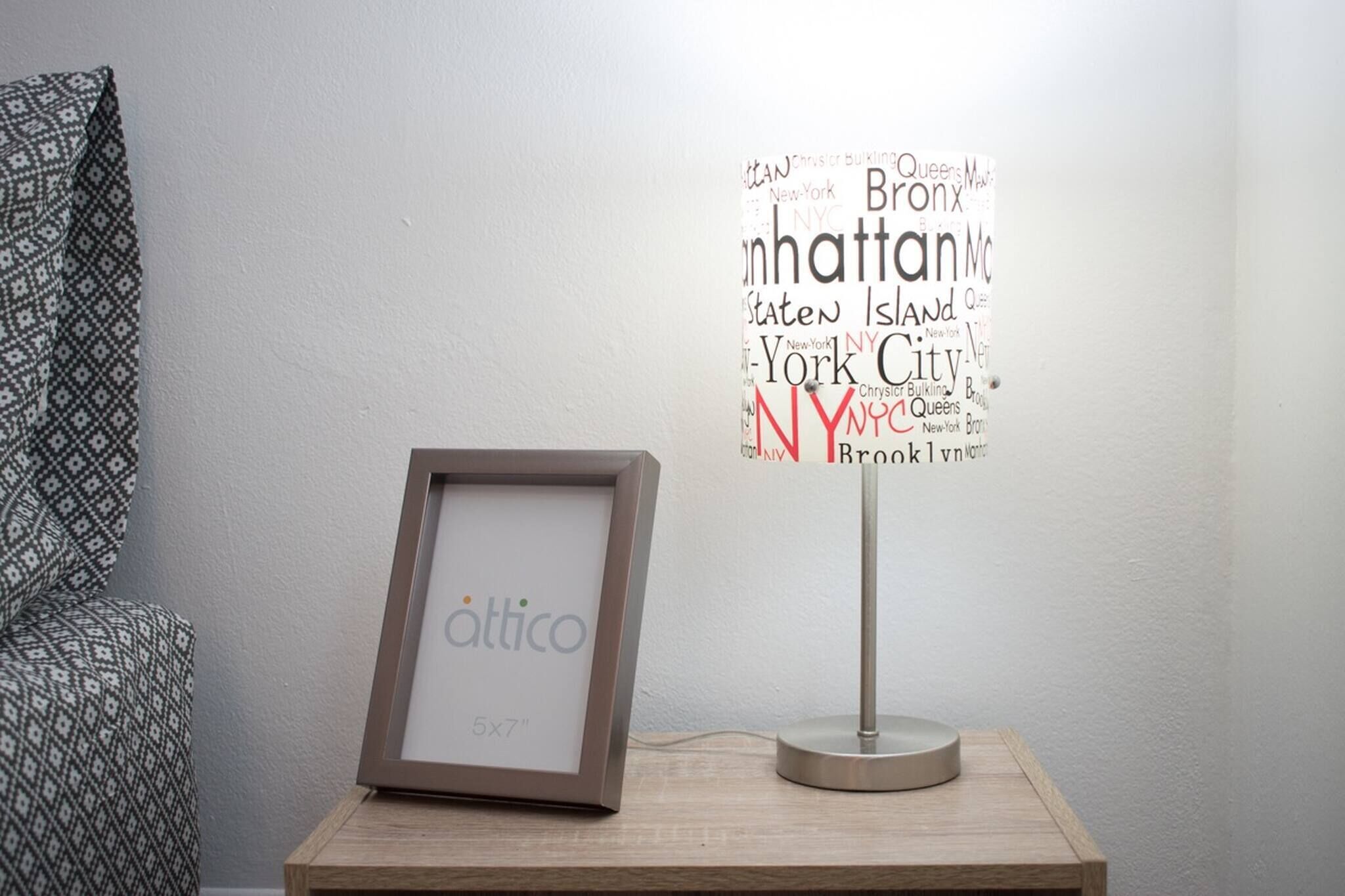 A framed picture on a wooden table, a wall with a word cloud, and a modern lamp.