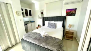 Un dormitorio con cama, mesita de noche, reloj y un cuadro en la pared.
