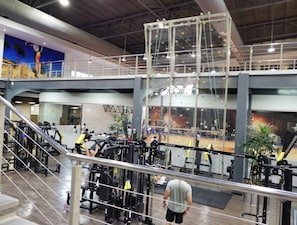 Un gimnasio de varios niveles con diferentes equipos de ejercicio, una pared de escalada y una escalera.
