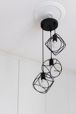 Eine deckenhohe Leuchte mit drei kugelförmigen Lampen, jeweils in Drahtgestellen eingefasst.
