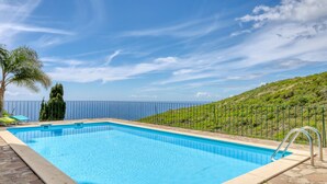 A swimming pool with a view of the sea, a stone deck, and a metal fence. - Verde Água Garajau, a Home in Madeira (Santa Cruz)