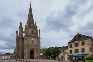 A historic cathedral with a clock tower, a cobblestone square, and a building with a sign for 'Hotel de l'Industrie.'