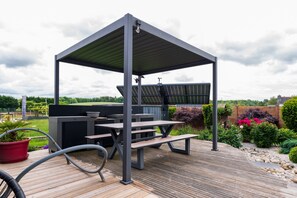 A covered outdoor area with a grill, picnic tables, and a wooden deck. - Guest Room "La chambre loft" in Modern Loft with Shared Terrace and Wi-Fi in Hennebont (Hennebont)