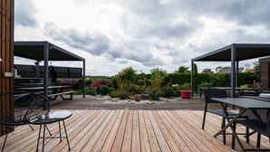 A wooden deck with outdoor seating and solar panels in the background. - Guest Room "La chambre loft" in Modern Loft with Shared Terrace and Wi-Fi in Hennebont (Hennebont)