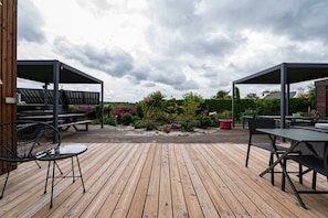 A wooden deck with outdoor seating and solar panels in the background. - Guest Room "La chambre loft" in Modern Loft with Shared Terrace and Wi-Fi in Hennebont (Hennebont)