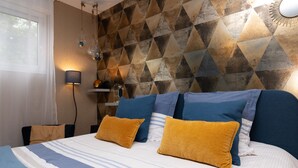 A bedroom with a bed, pillows, a lamp, a geometric wall pattern, and a window. - Guest Room "La chambre loft" in Modern Loft with Shared Terrace and Wi-Fi in Hennebont (Hennebont)