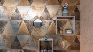 A geometric patterned wall with a mirror, a sunburst decoration, and two shelves with decorative items. - Guest Room "La chambre loft" in Modern Loft with Shared Terrace and Wi-Fi in Hennebont (Hennebont)