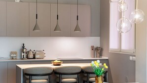 Una cocina moderna con luces colgantes, una isla central con taburetes y un florero con flores.