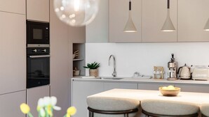 Una cocina moderna con electrodomésticos integrados, iluminación colgante y una isla central con asientos.