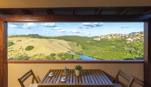Ein Balkon mit Tisch, Stühlen, einer Kaffeemaschine, Tassen und einem Blumentopf.