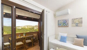 Ein Balkon mit Tisch und Stühlen, eine Couch mit Kissen und ein Bild an der Wand.