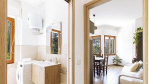 Ein modernes Badezimmer mit integrierter Waschmaschine, einem großen Spiegel und einem Fenster.