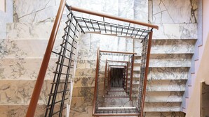Una escalera de mármol con barandilla metálica y pasamanos de seguridad.