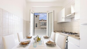Una cocina estrecha con una mesa lista para el desayuno, vista a través de una puerta abierta y una estufa moderna.
