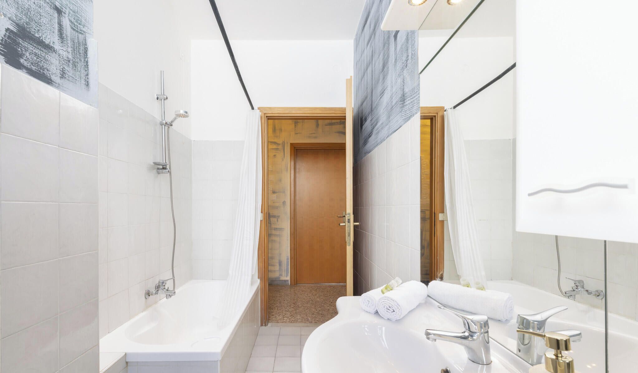 A modern bathroom with a bathtub, a shower, a sink, and a mirror.