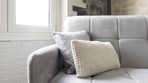 Un sillón tapizado en gris con un cojín blanco con textura.