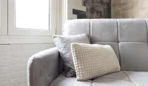 A grey upholstered armchair with a white textured pillow. - 3BR Family Apartment by Propertize (Cagliari)