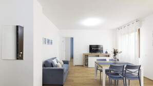 Ett modernt vardagsrum med en soffa, en tv och en matplats.