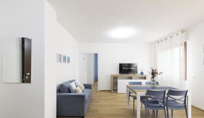A modern living room with a sofa, TV, and dining area. - Blue Modern Apartment (Monserrato)