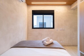A hotel room with a bed, a window, and a wooden ceiling.