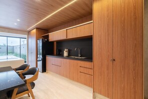 A modern kitchen with wooden cabinets, a black countertop, and a dining area with a table and chairs.
